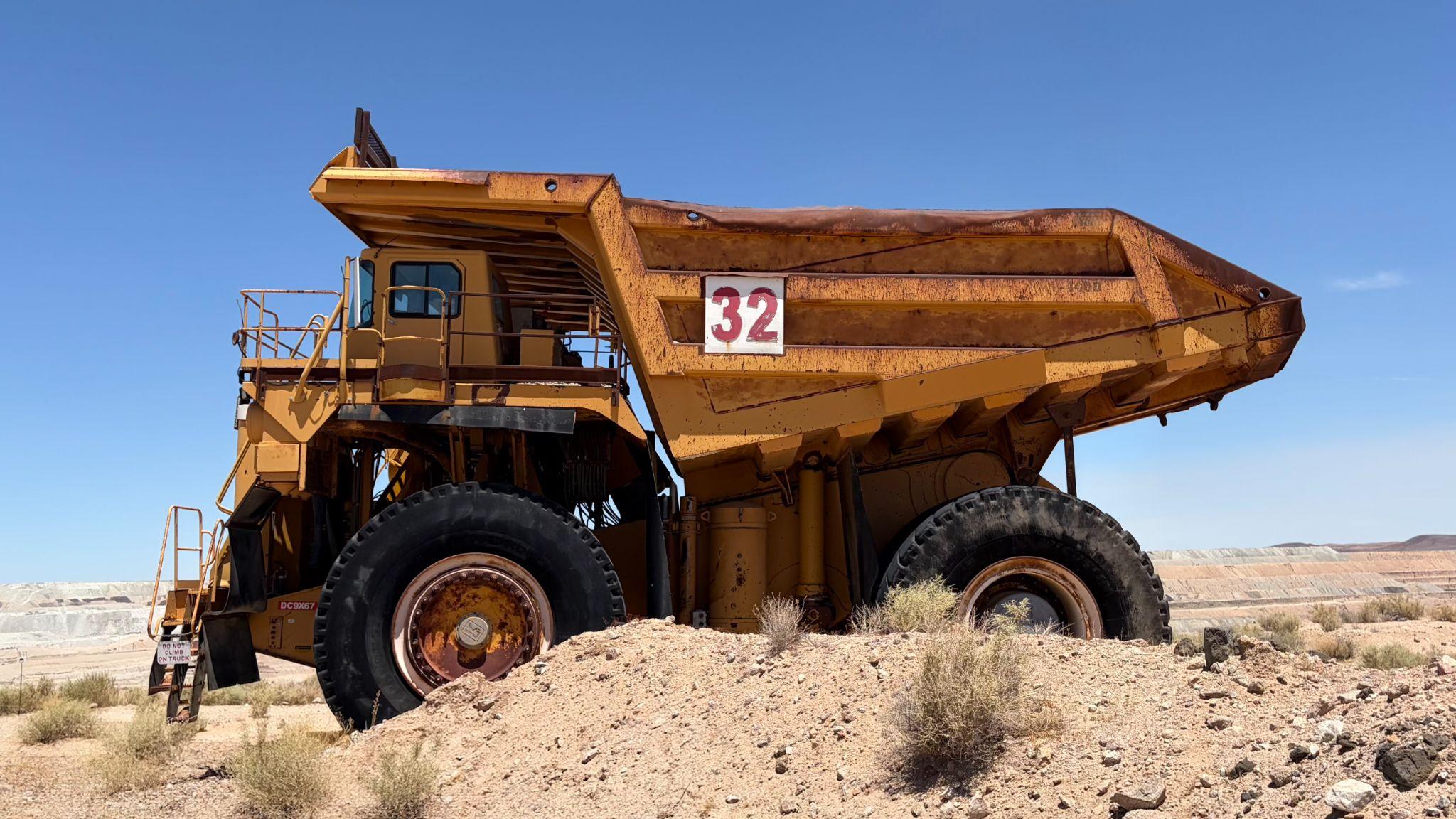 A large, weathered yellow mining haul truck parked in the desert